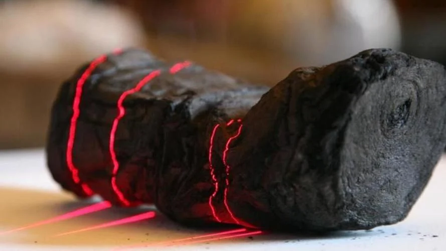 A Herculaneum scroll, charred and buried in a library near Pompeii, is scanned with red laser lines at Institut de France by Brent Seales, a computer science professor at the University of Kentucky. 