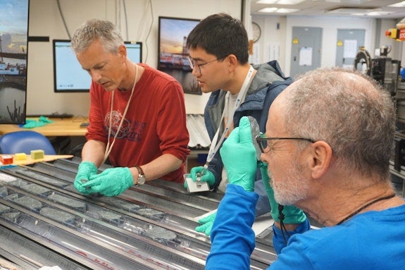 Professor Johan Lissenberg from Cardiff University’s School of Earth and Environmental Sciences (left) and colleagues Dr Haiyang Liu and Professor Mark Reagan analyzing the cores, which were recovered from a “tectonic window” on the Mid-Atlantic Ridge. 