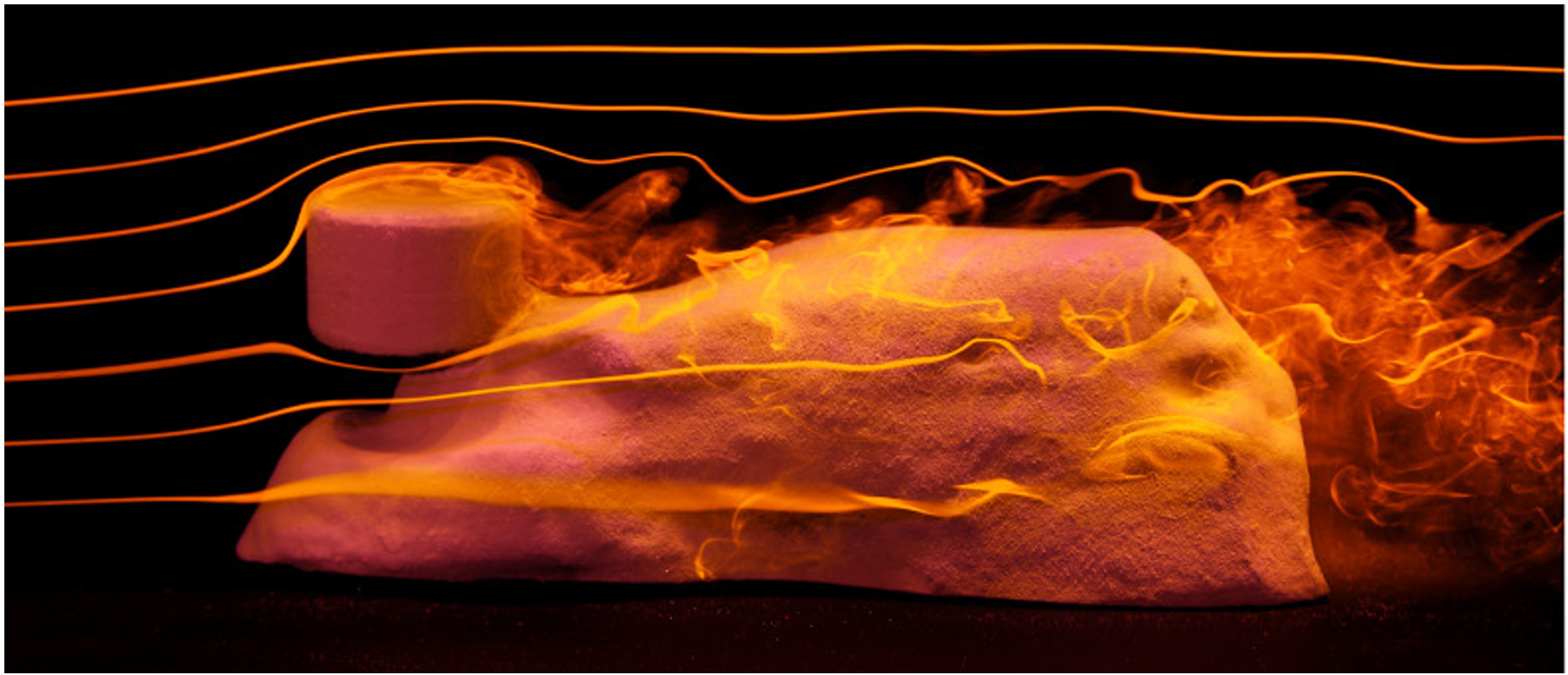 A lab Sphinx is carved through an experiment that replicates the wind moving against once-shapeless mounds of clay, with harder material becoming the “head” of the lion and other features—such as an undercut “neck,” “paws” laid out in front on the ground, and arched “back”—developing. 