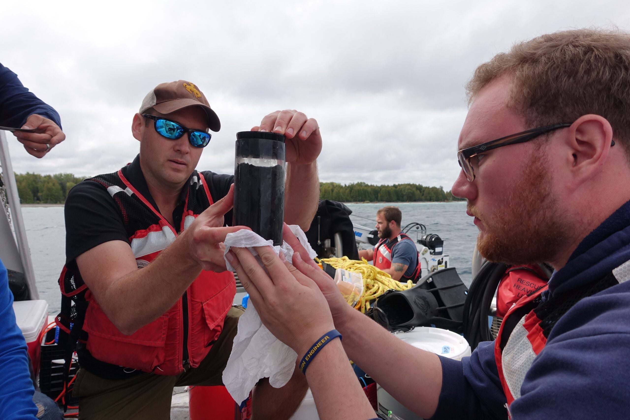 U-M geomicrobiologist and oceanographer Greg Dick, left, and U-M environmental engineering alumnus Kirk Olsen examine one of the sediment cores collected from the Middle Island Sinkhole in Lake Huron. The cores contain samples of microbial mats that are analogs for the types of microorganisms that thrived on Earth billions of years ago. 