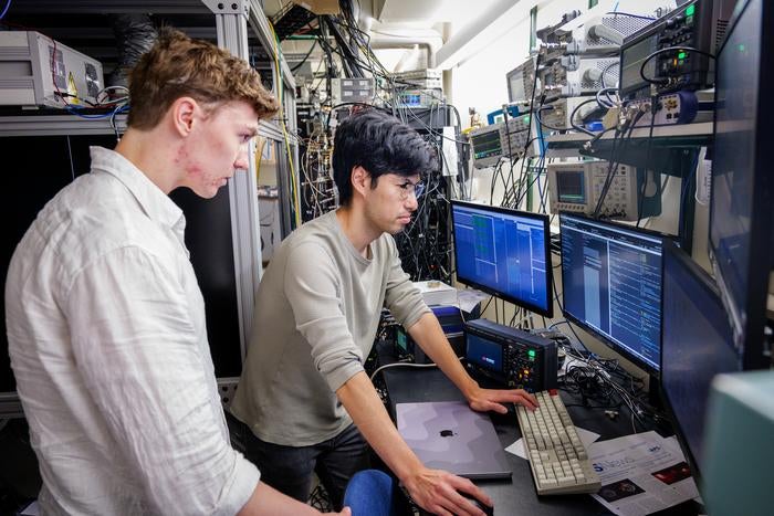 Graduate students Theo Lukin Yelin, left, and Alec Cao, right, monitor an optical atomic clock via computer.


