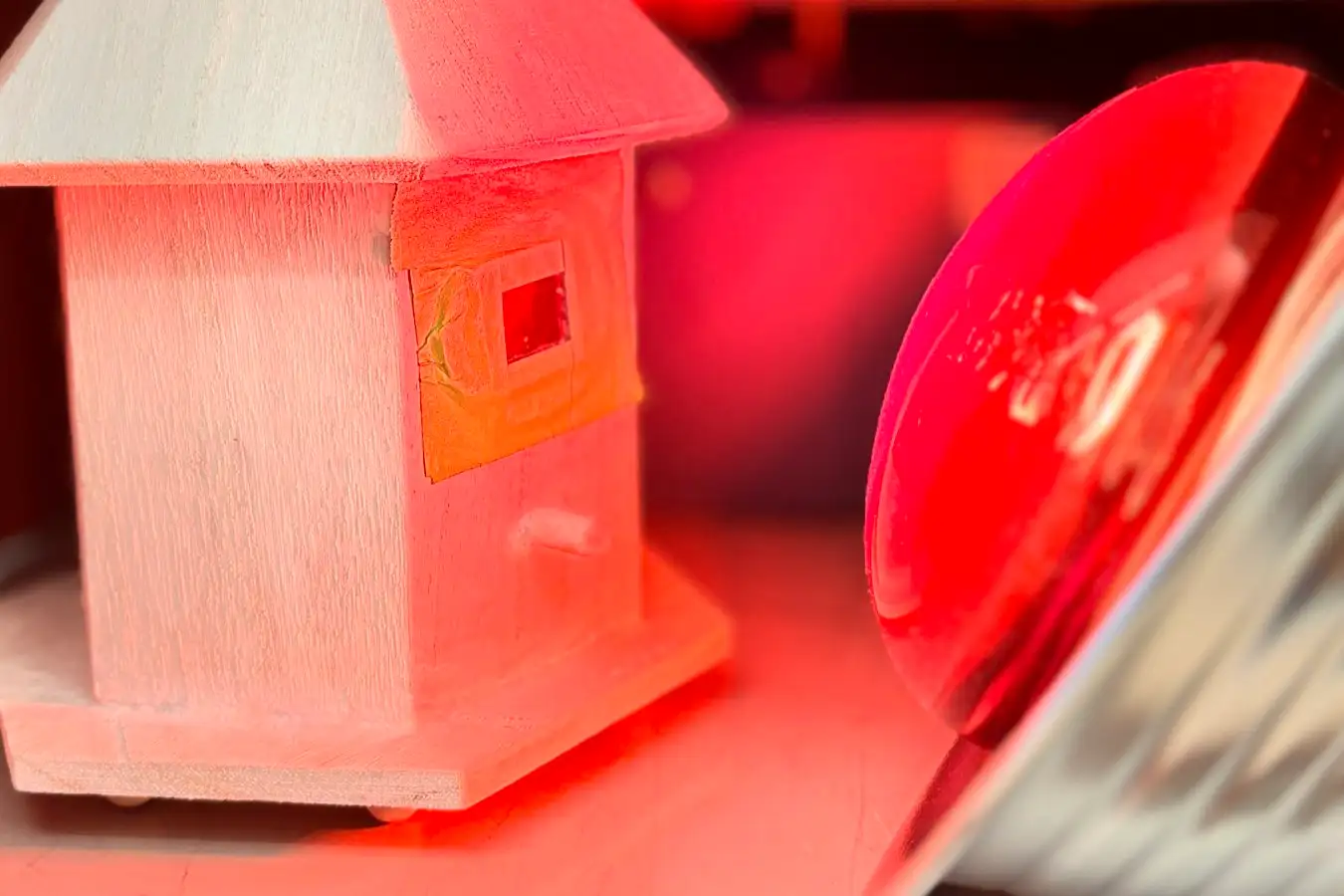 A birdhouse featuring a transparent wooden window was positioned near a heat lamp to evaluate the material's thermal characteristics.