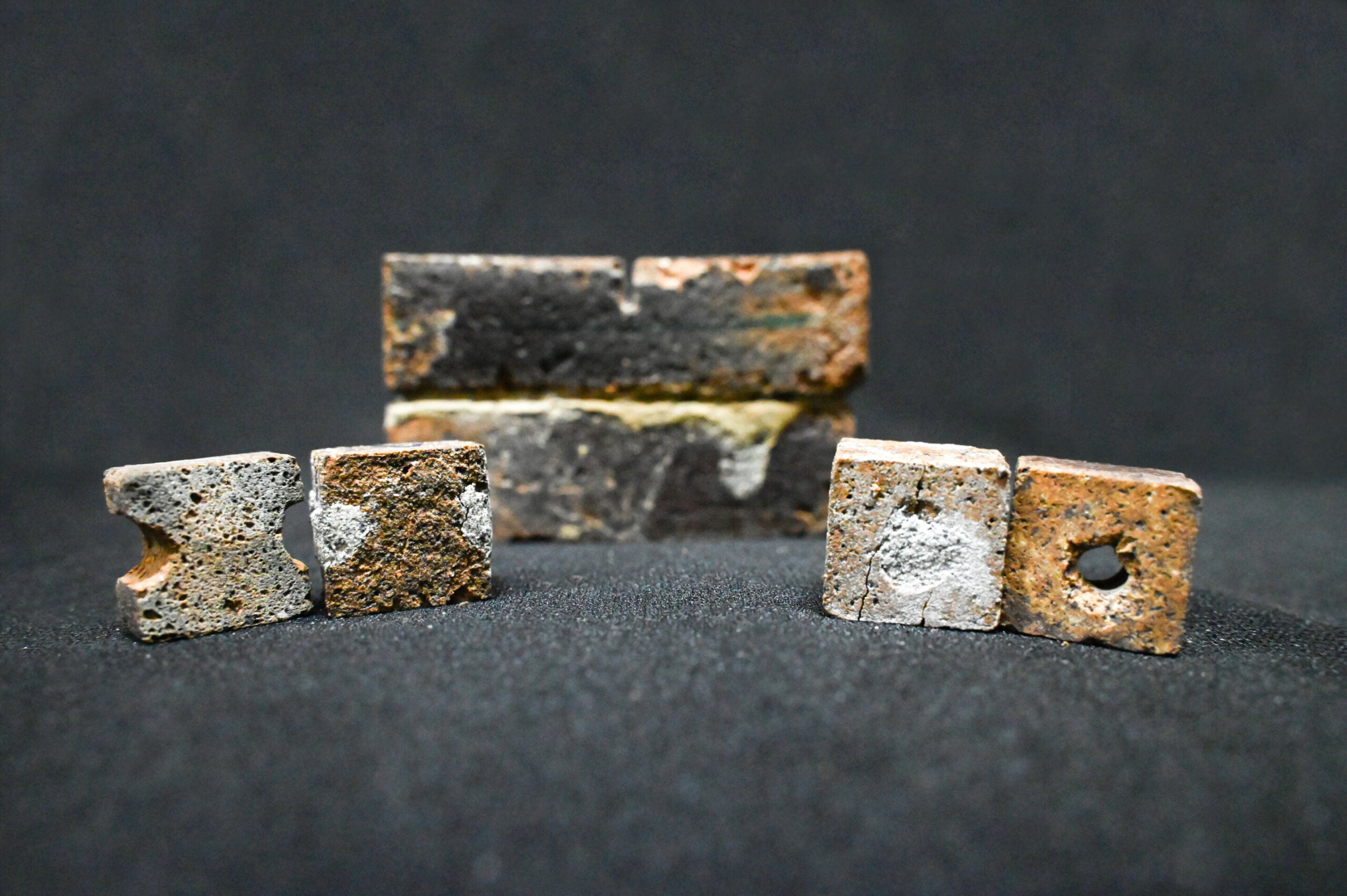 Bricks with artificially created flaws, alongside bricks repaired using the bacteria-filled slurry. 