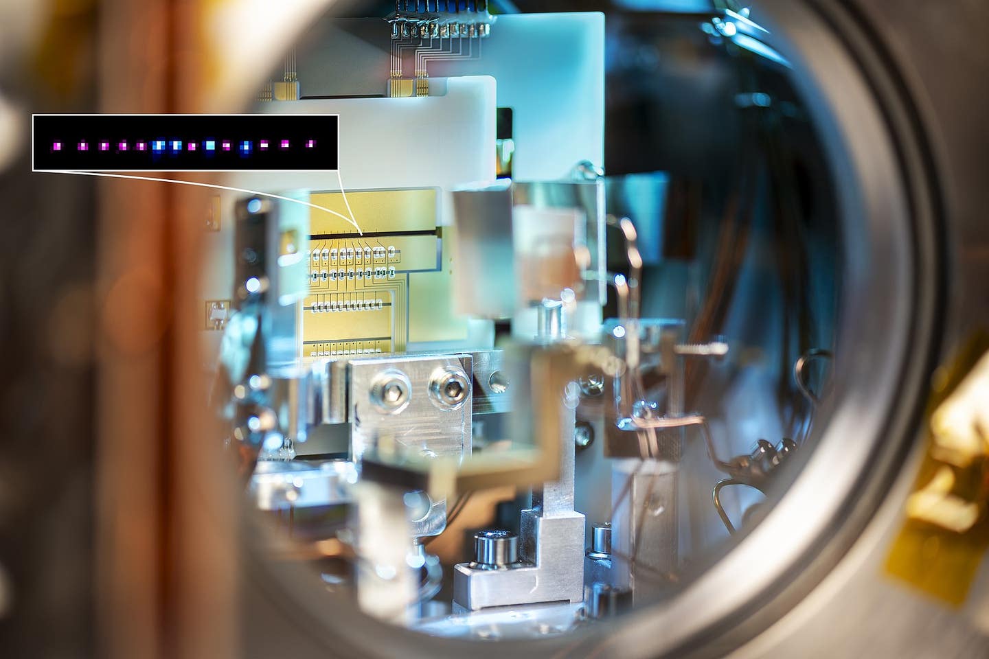 The ion trap of the new In+/Yb+-crystal clock in its vacuum chamber. The Ions are trapped in the gap that can be seen in the middle of the picture between the gold electrodes (target). A shown-up picture: a crystal from indium- (pink) and ytterbium (blue) ions.