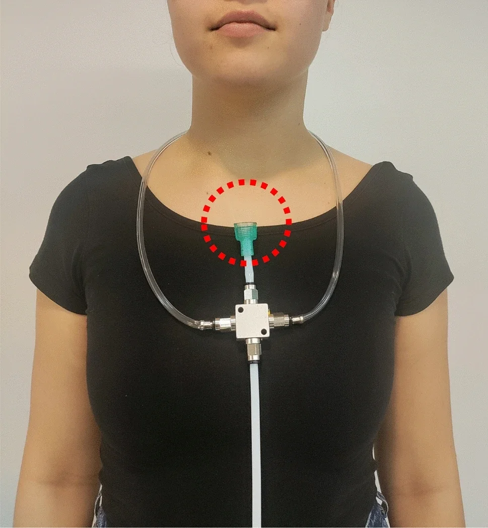 A user wearing the olfactory necklace display; the tube outlet that directed odorous air towards the nasal area is highlighted with a circle.