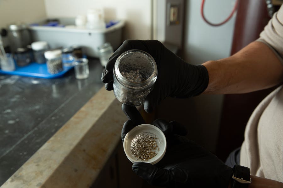 The new process starts with pellets of recycled aluminum (in jar) that react with seawater to produce pure hydrogen. The team found that if scaled up, the process could generate “green” hydrogen with a low-carbon footprint.