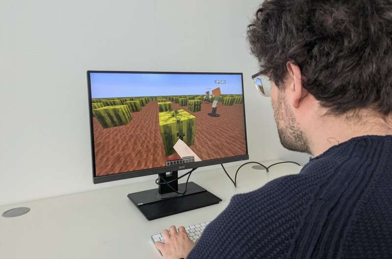 A person interacts with a custom-built Minecraft environment used to study adaptive social learning in a virtual foraging experiment.