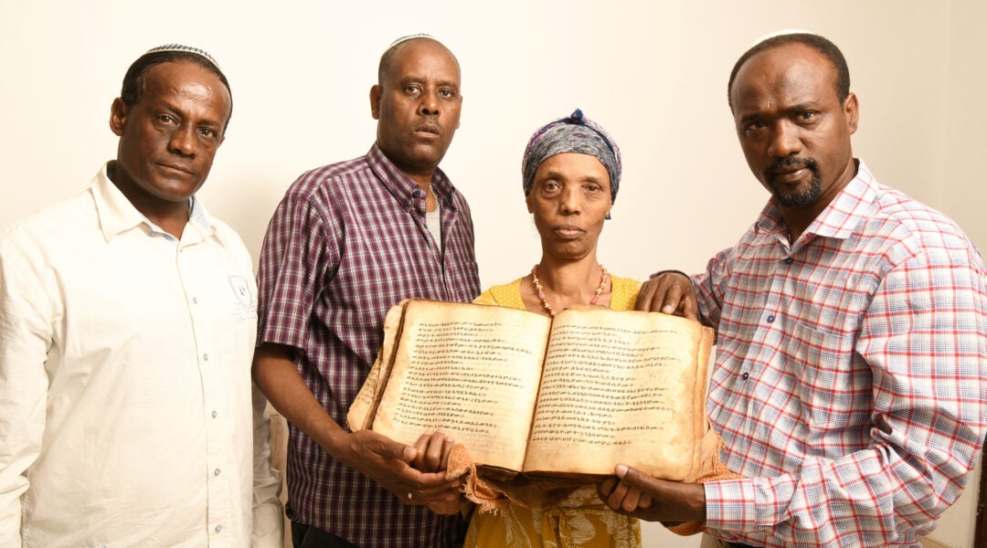 Ayanawo Ferada Senebato, right, and his family shown in Ashkelon, Israel, holding an ancient Orit book that they retrieved near Gondar, Ethiopia