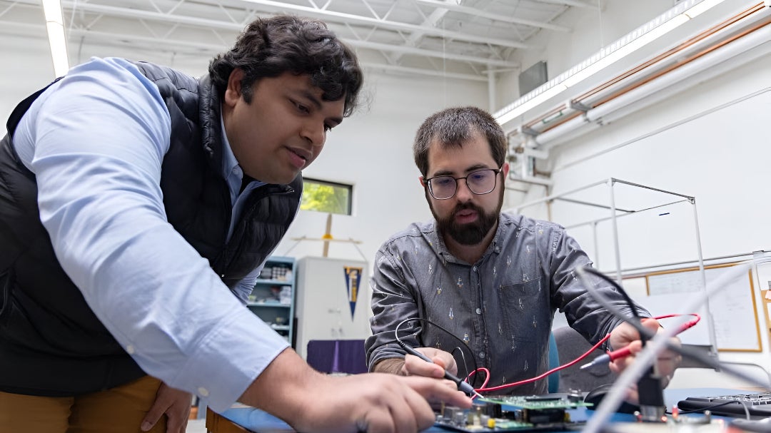 UC Davis graduate students Ayush Patnaik (left) and Adam Zufall (right) working on a payload that will travel into space this fall. The payload is a digital twin that will use AI software to measure the activity and predict the future state of the battery.