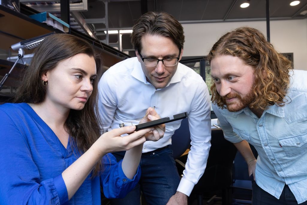 Erin Kunz, Frank Willett, and Benyamin Meschede-Krasa inspect a microelectrode array.