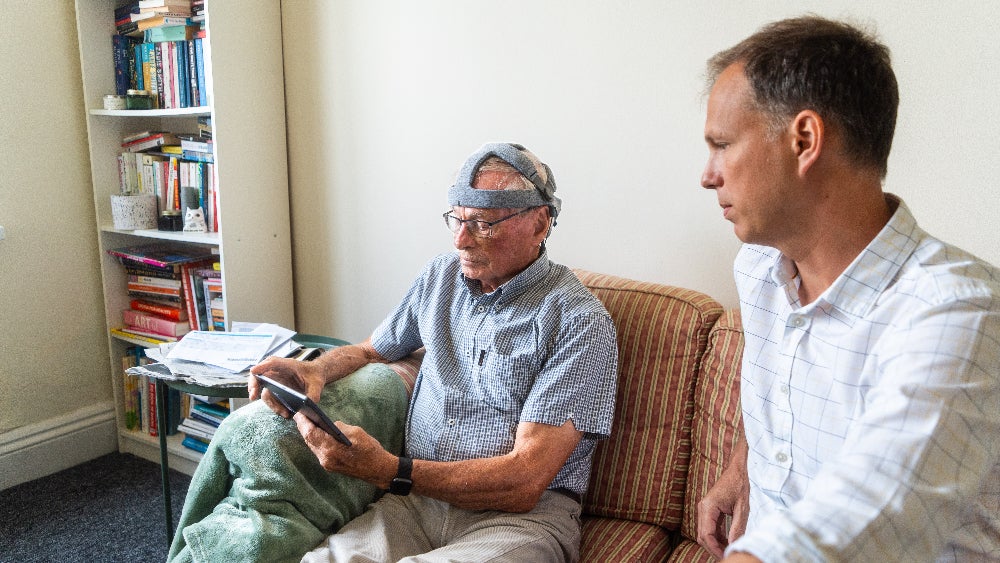 John Stennard, a healthy study volunteer taking the Fastball test in his home, with Dr George Stohart from the University of Bath. 