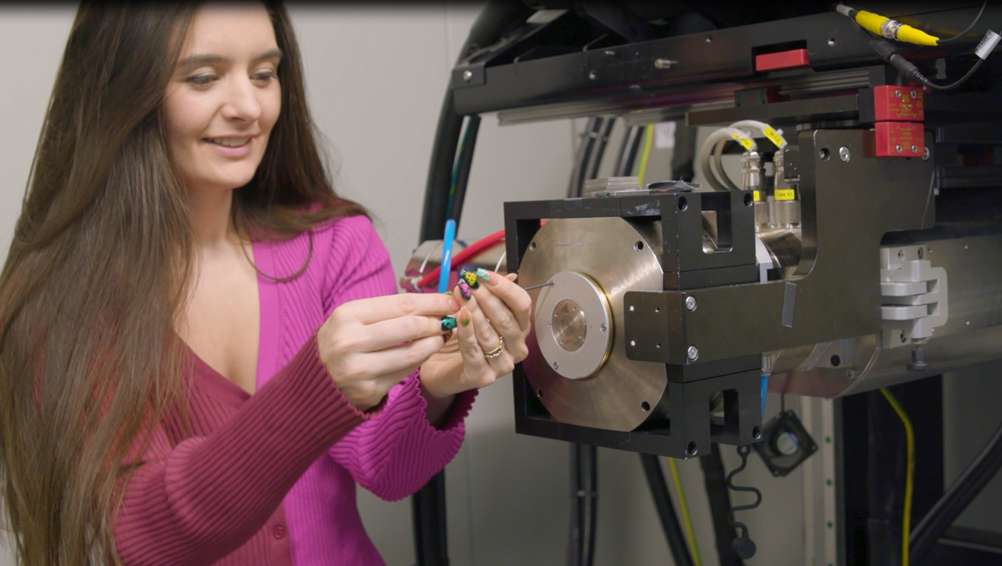 Noelle Collins mounts the packaged multi-metal patterned target on the X-ray tube at Sandia National Laboratories.