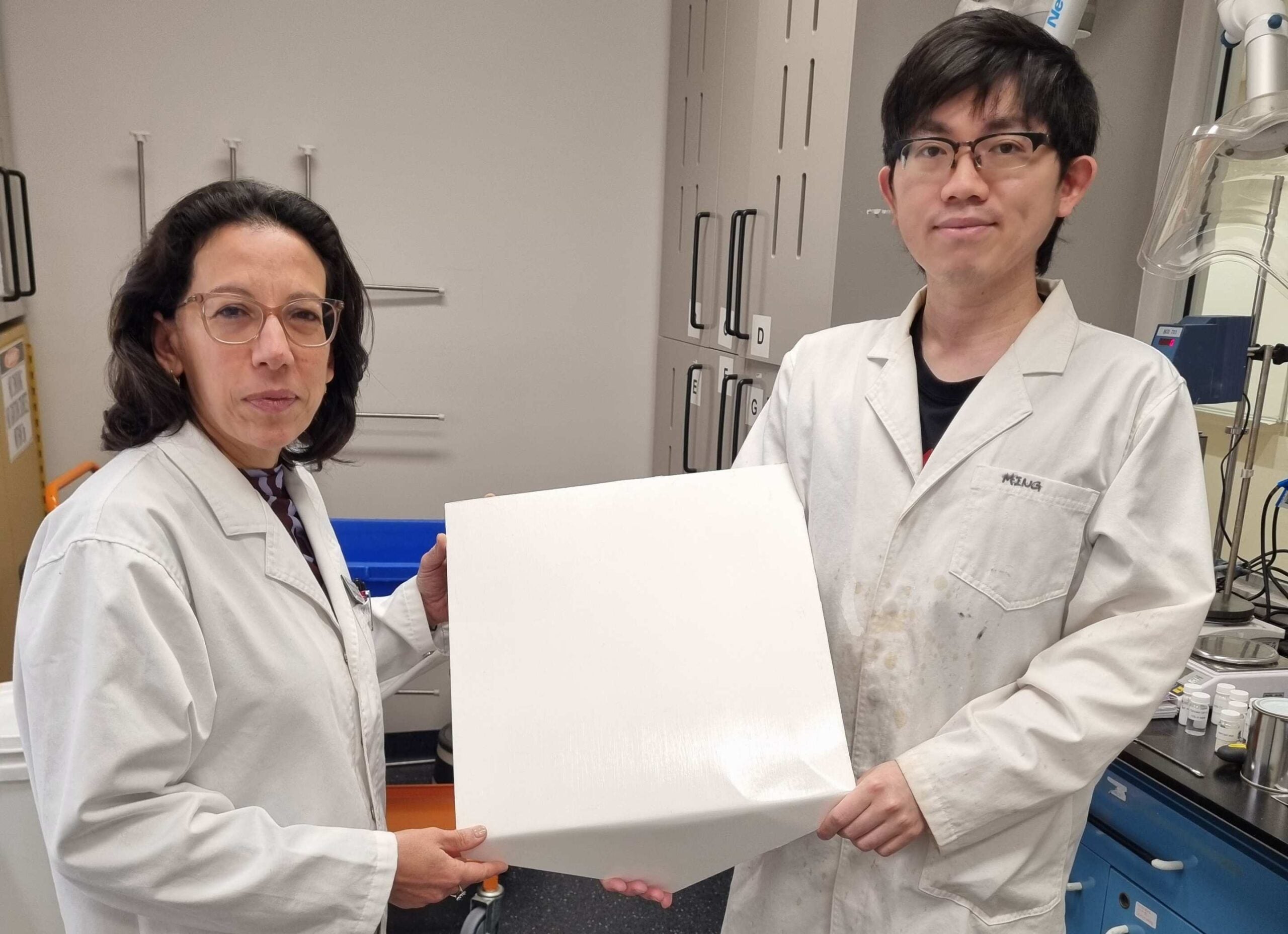 Professor Chiara Neto (left) and Dr Ming Chiu holding one of the polymer-coated tiles used in the experiment.