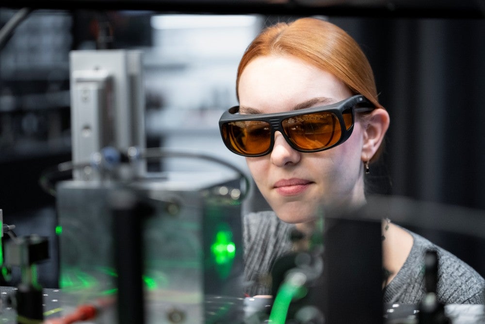 With protective eyewear, Stöllner takes a glimpse into the experimental chamber (in the foreground), where two laser beams trap a single particle.