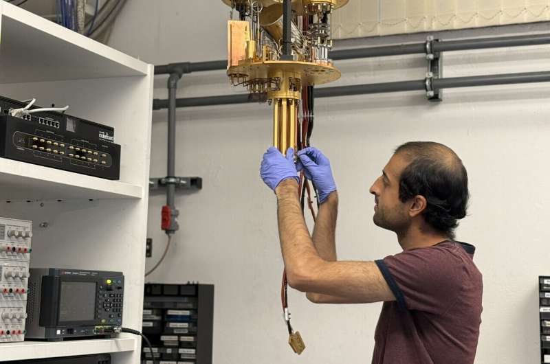 PhD student Vivek Wadhia sets up the dilution fridge inside which the quantum clock experiment was carried out.