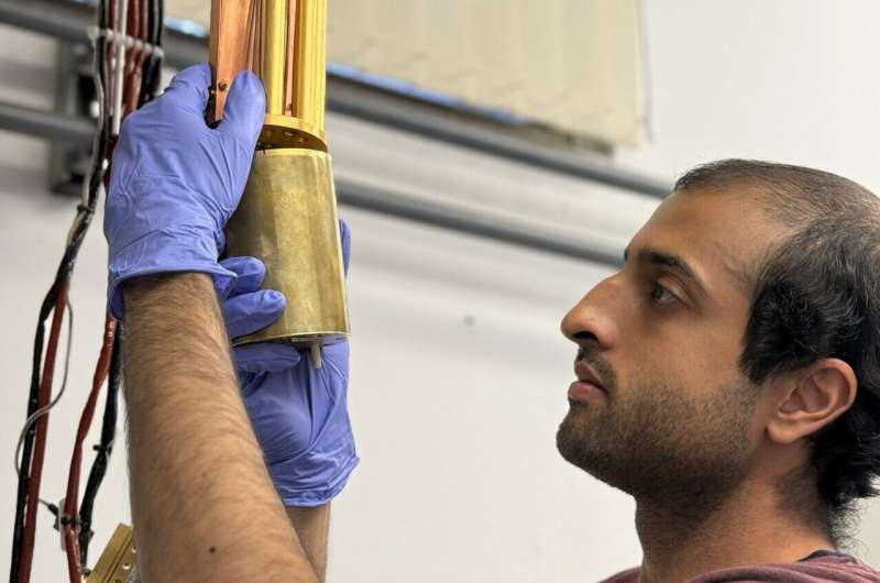 PhD student Vivek Wadhia sets up the dilution fridge inside which the quantum clock experiment was carried out.