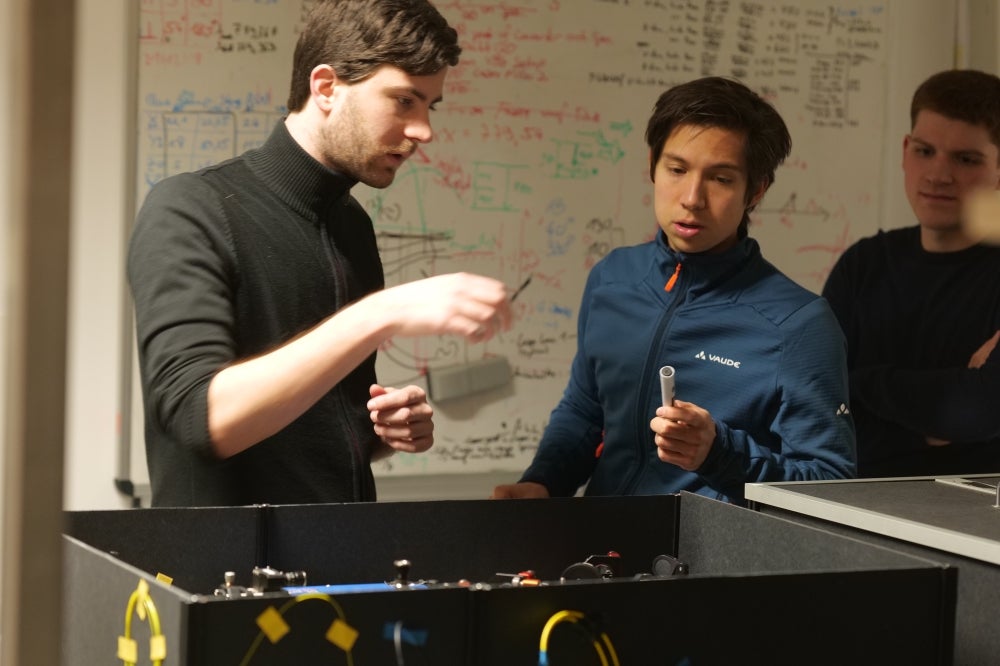 Tobias Bauer (left) and Marlon Schäfer (right) from Saarland University and Tim Strobel (center) from the University of Stuttgart preparing for an experiment with mobile quantum frequency converters.