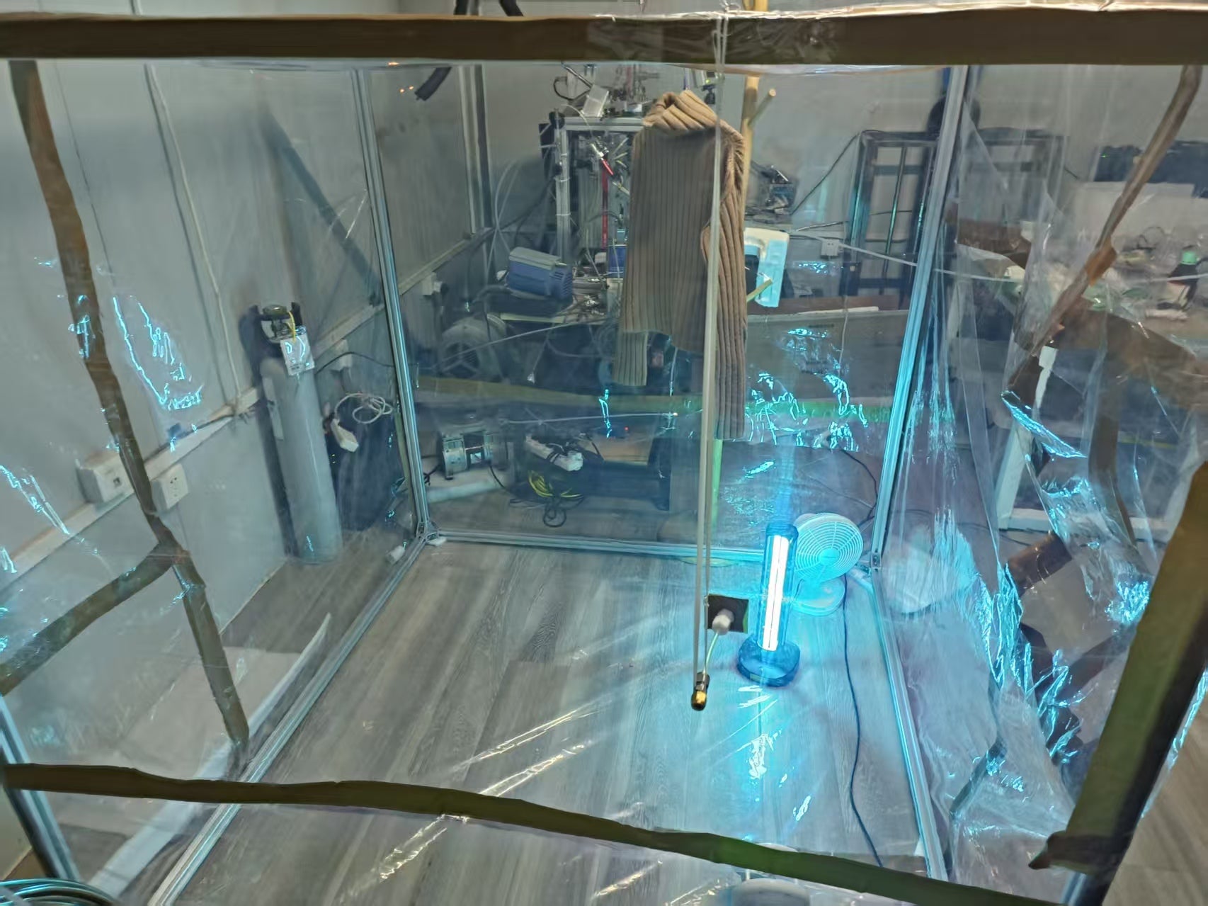 A wool sweater exposed to thirdhand smoke is suspended within a custom-built Teflon film chamber for controlled ozone oxidation experiments. 