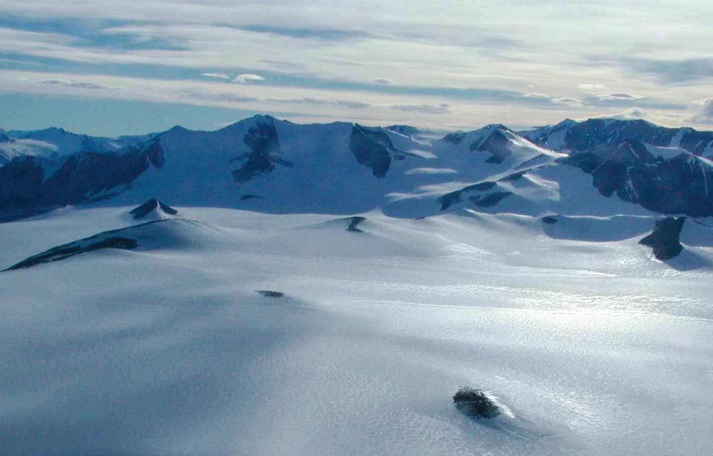 Ice conceals a rugged landscape. A view over the Wilson Piedmont in Antarctica shows examples of the ice surface and what the buried topography may look like.