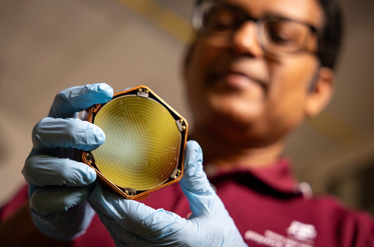 Dr. Rupak Mahapatra, an experimental particle physicist, holds a SuperCDMS detector. The highly sensitive devices, which are fabricated at Texas A&M University, are deepening the search for dark matter and have potential applications in quantum computing.