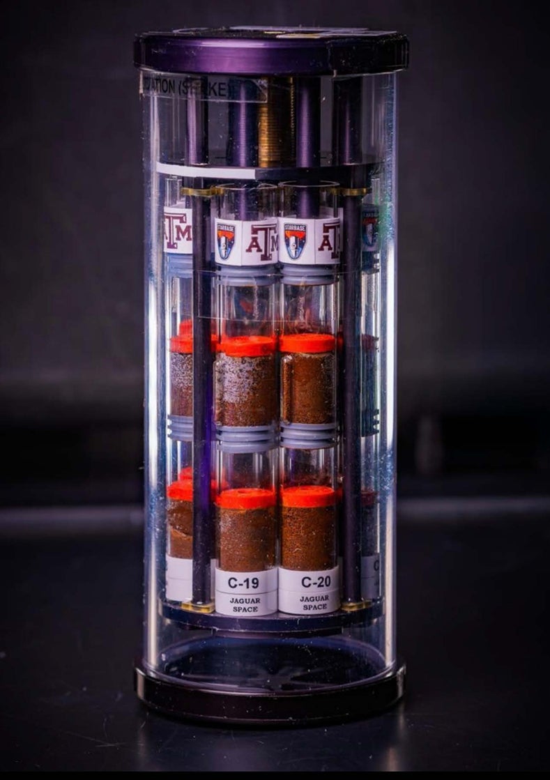 A canister with small vials in it with red caps.