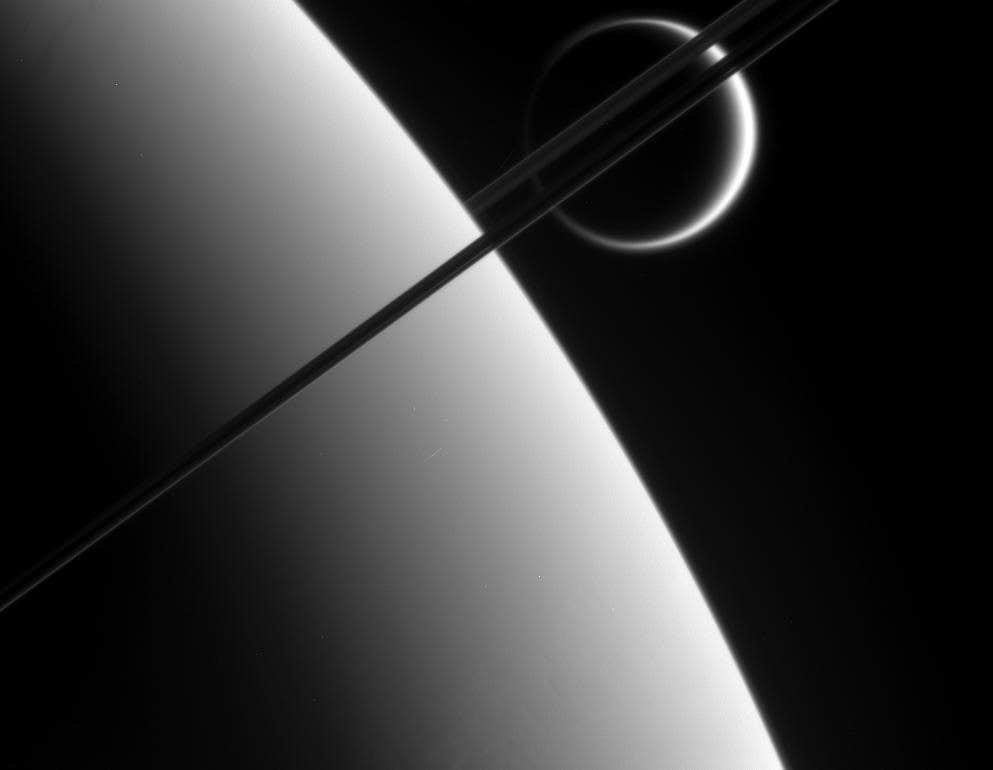 This view was taken from above the ringplane and looks toward the unlit side of the rings. Here, the probe gazes upon Titan in the distance beyond Saturn and its dark and graceful rings.