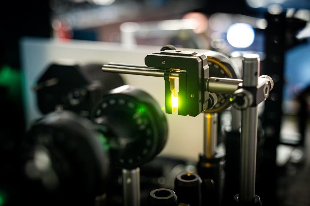 Examining a lead-halide perovskite crystal in the lab using optical methods. The sample (center right) glows green.