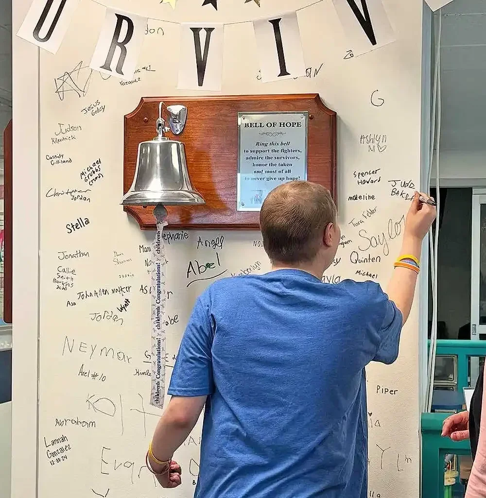 Jude Baker signing the wall and ringing the bell on his last day of chemotherapy.