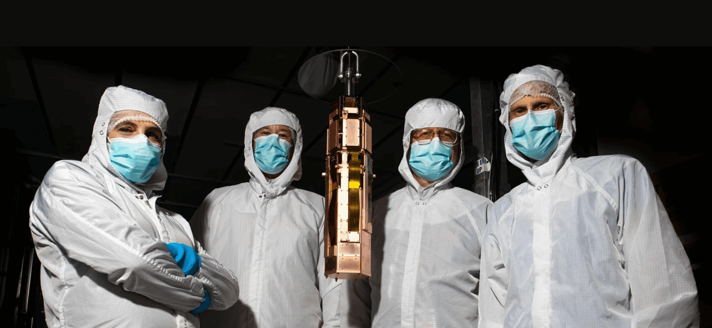 From left, SLAC research technical manager Concetta "Tina" Cartaro, staff scientist Paul Brink, senior staff scientist Richard Partridge and Santa Clara University physics professor Betty Young with the fourth, and final, SuperCDMS tower, in the SLAC Building 033 clean room.