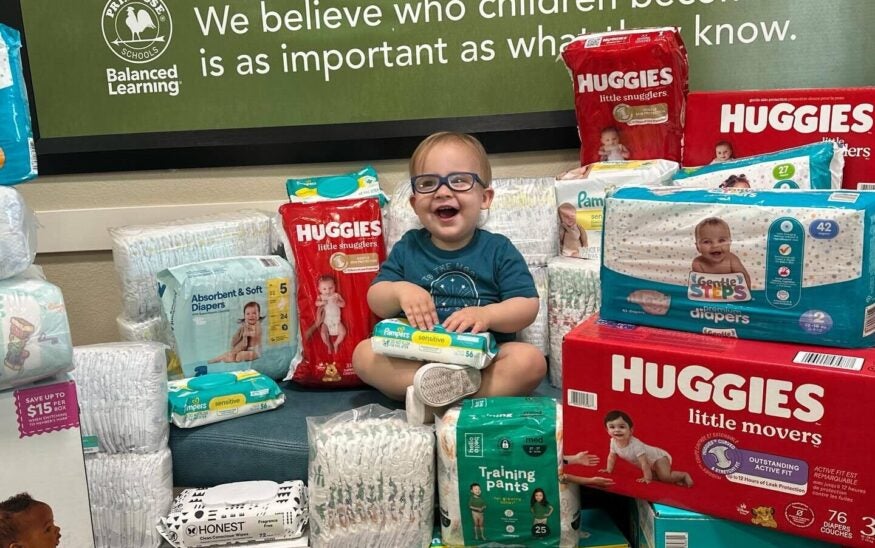 At a Primrose School, a baby poses with the items donated by Primrose preschoolers in Oklahoma City. 