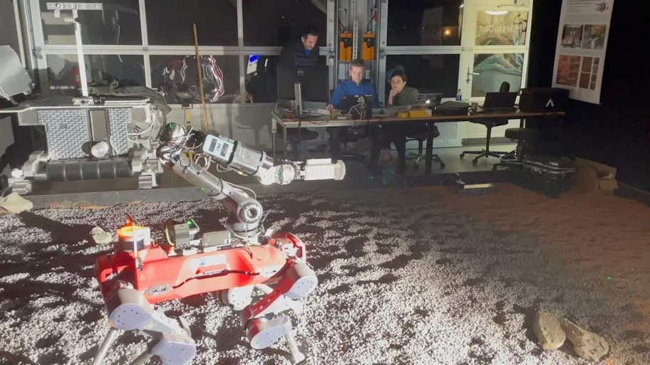 Setup of legged robot operation on the testbed, with the control room and operators in the background.