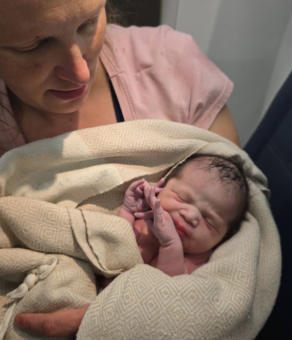 In this photo provided by Tina Fritz, Ashley Blair holds her daughter Brielle, who was born April 24, 2026, on a Delta Air Lines flight just as it was landing in Portland, Ore. 