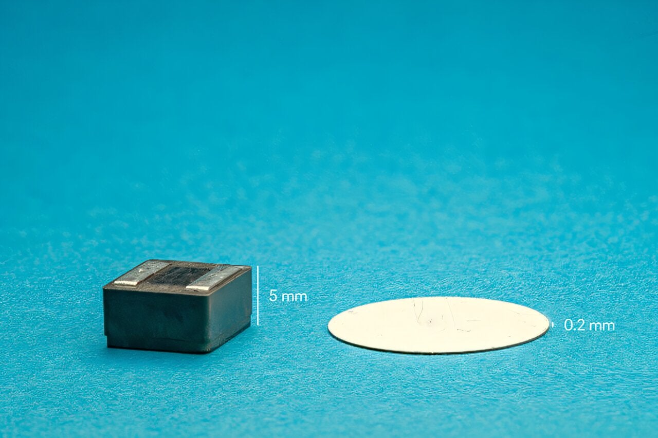 A piezoelectric resonator (white disk) used by the new chip to perform DC-DC step-down conversion. For comparison, an inductor that is typically used in traditional step-down converters is shown on the left.