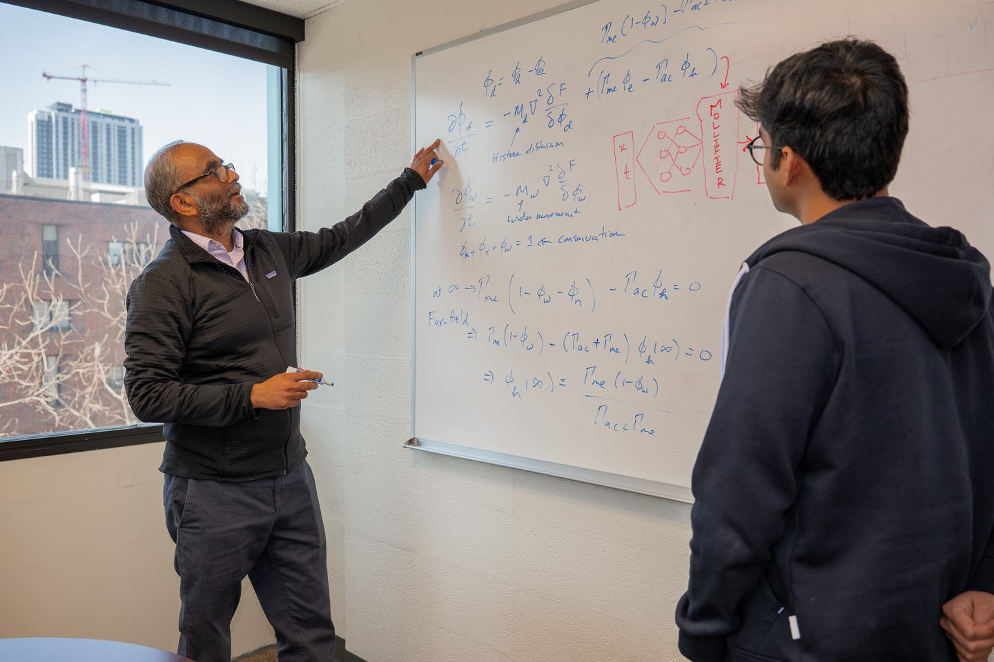 Vivek Shenoy, Eduardo D. Glandt President’s Distinguished Professor in Materials Science and Engineering (MSE), at left, walks through some of the mathematics behind mollifier layers, with doctoral candidate Vinayak Vinayak, at right.