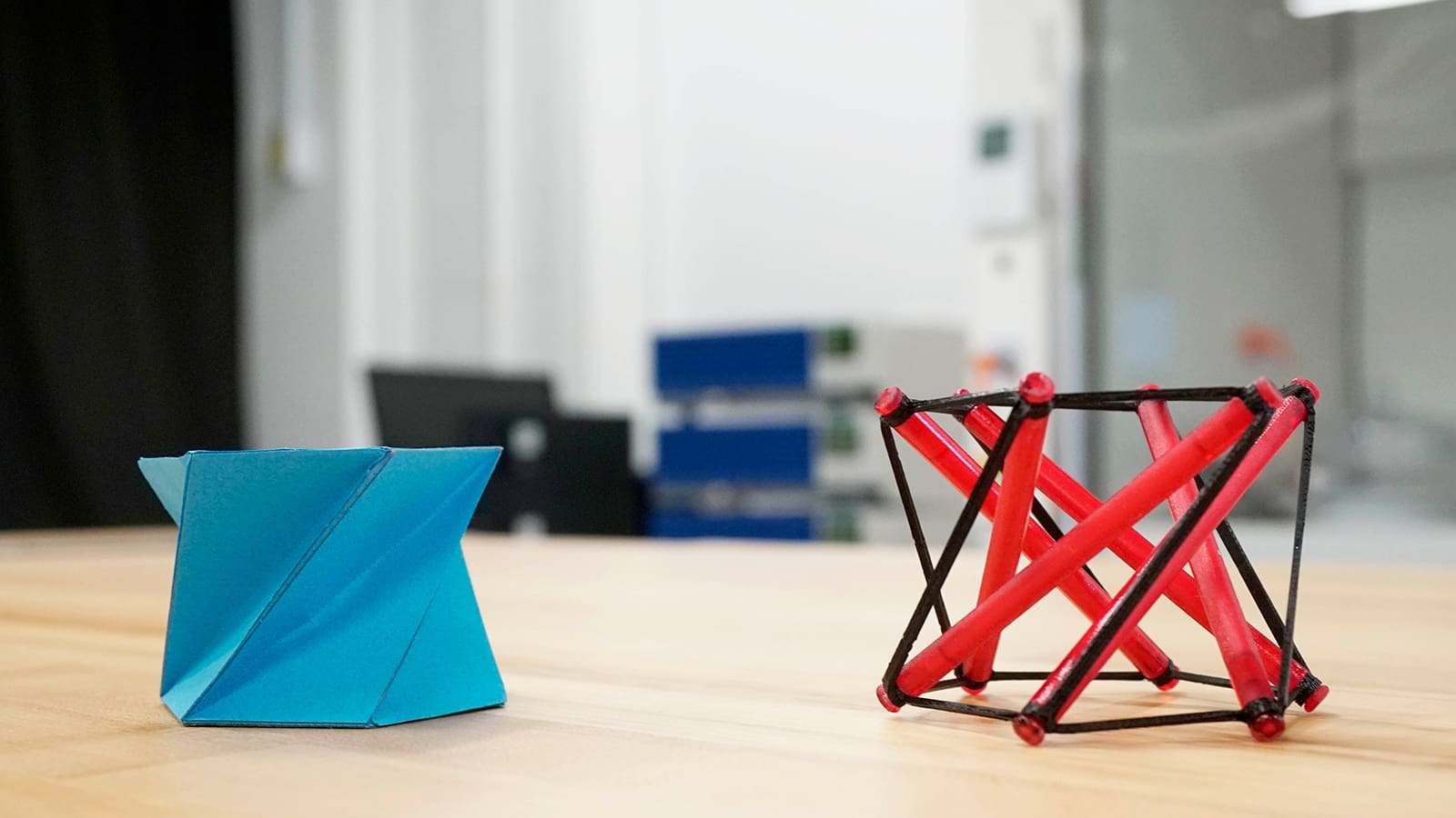 A object folded with origami next to an object balanced with tensegrity.