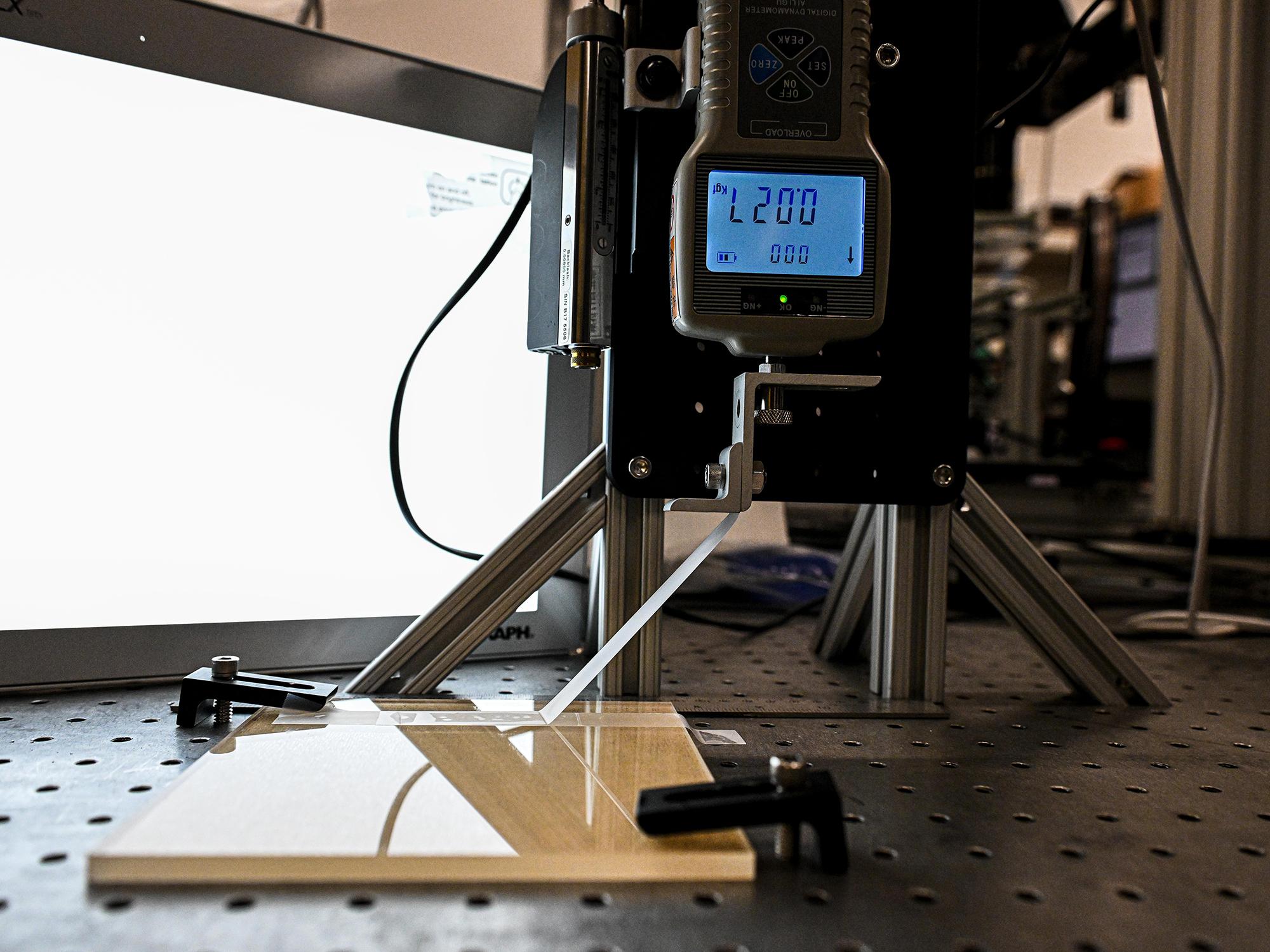 The research team built an automated device that can peel tape to designated distance, lay it back down and measure the amount of force needed to peel the tape. 