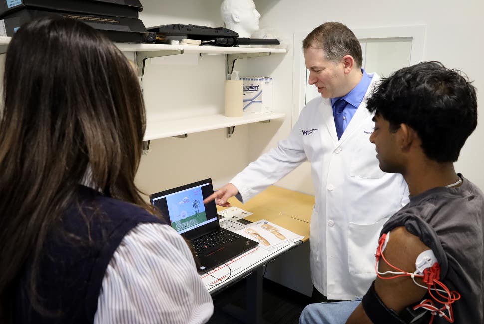 Dr. Marc Slutzky and study co-author Cynthia Gorski watch a lab member demo playing the video game in the lab.