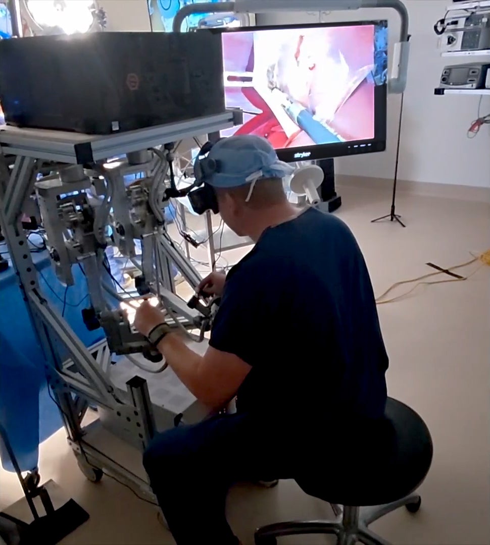 Ryan Broderick, MD, sits a teleoperation console and controls a robot during a gallbladder removal procedure.