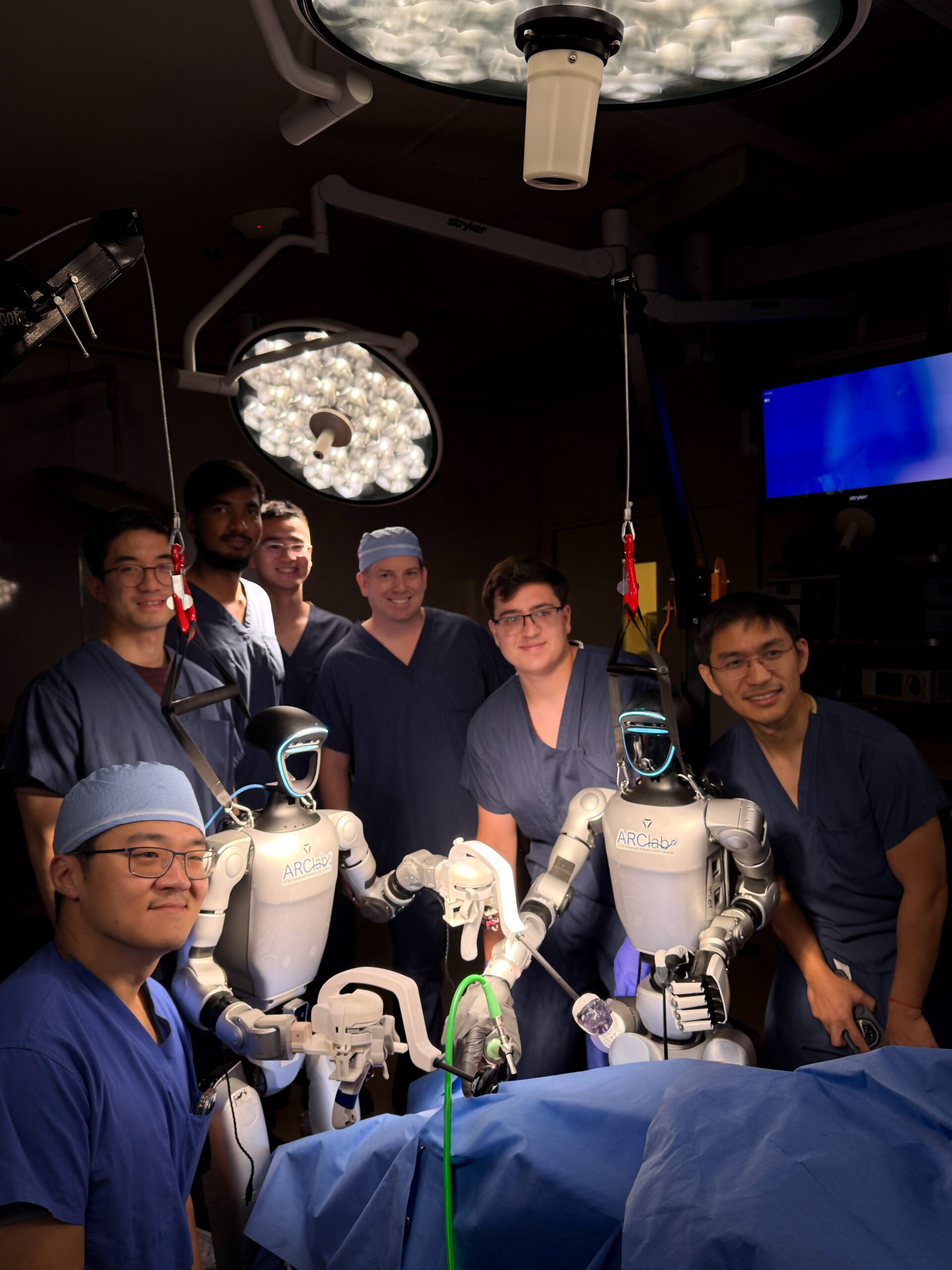 Researchers take a group photo with the two teleoperated robots.