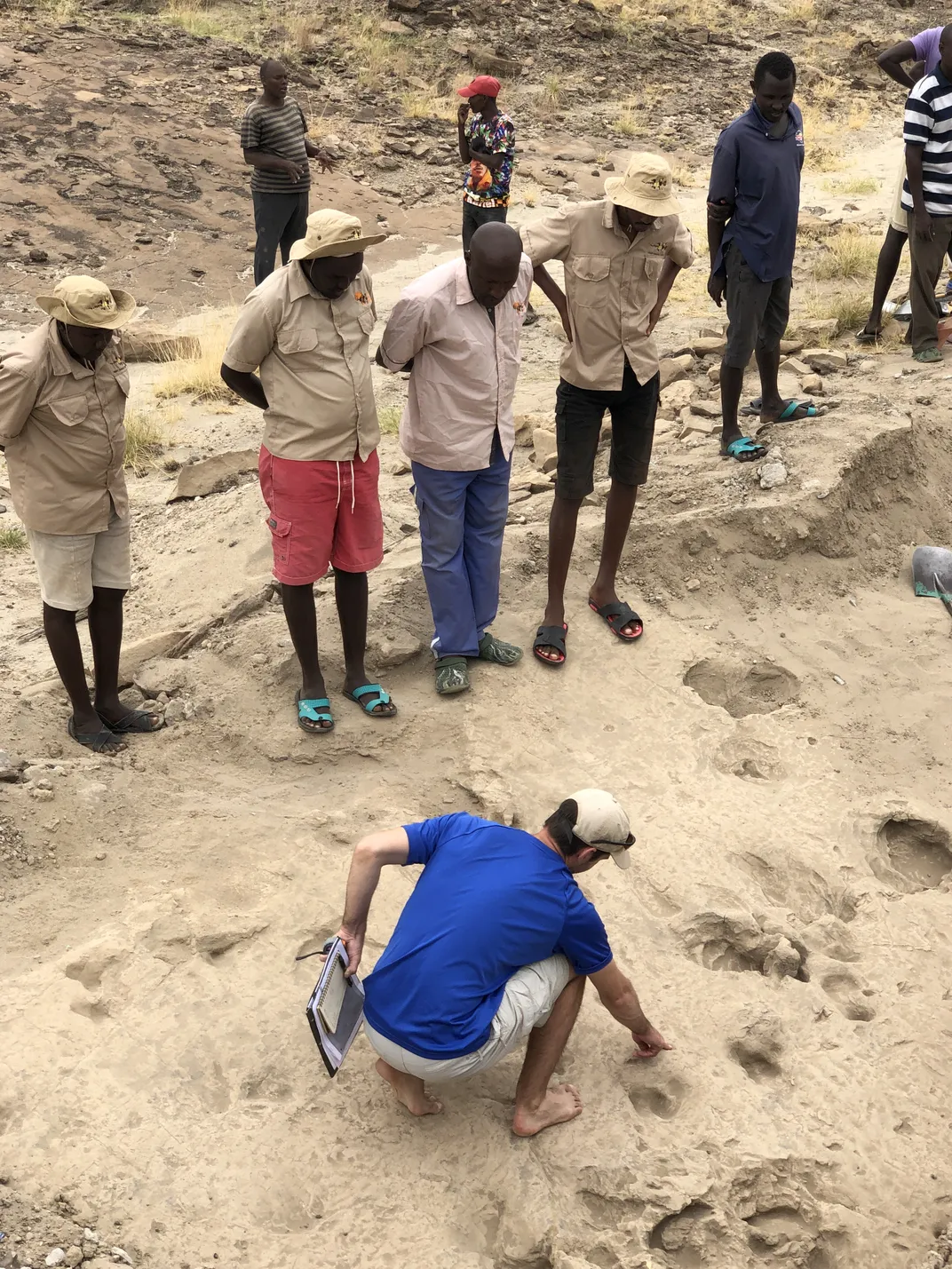 Kevin Hatala of Chatham University and the Max Planck Institute for Evolutionary Anthropology examines ancient footprints, highlighting hominin tracks preserved between the much larger impressions left by hippopotamuses.