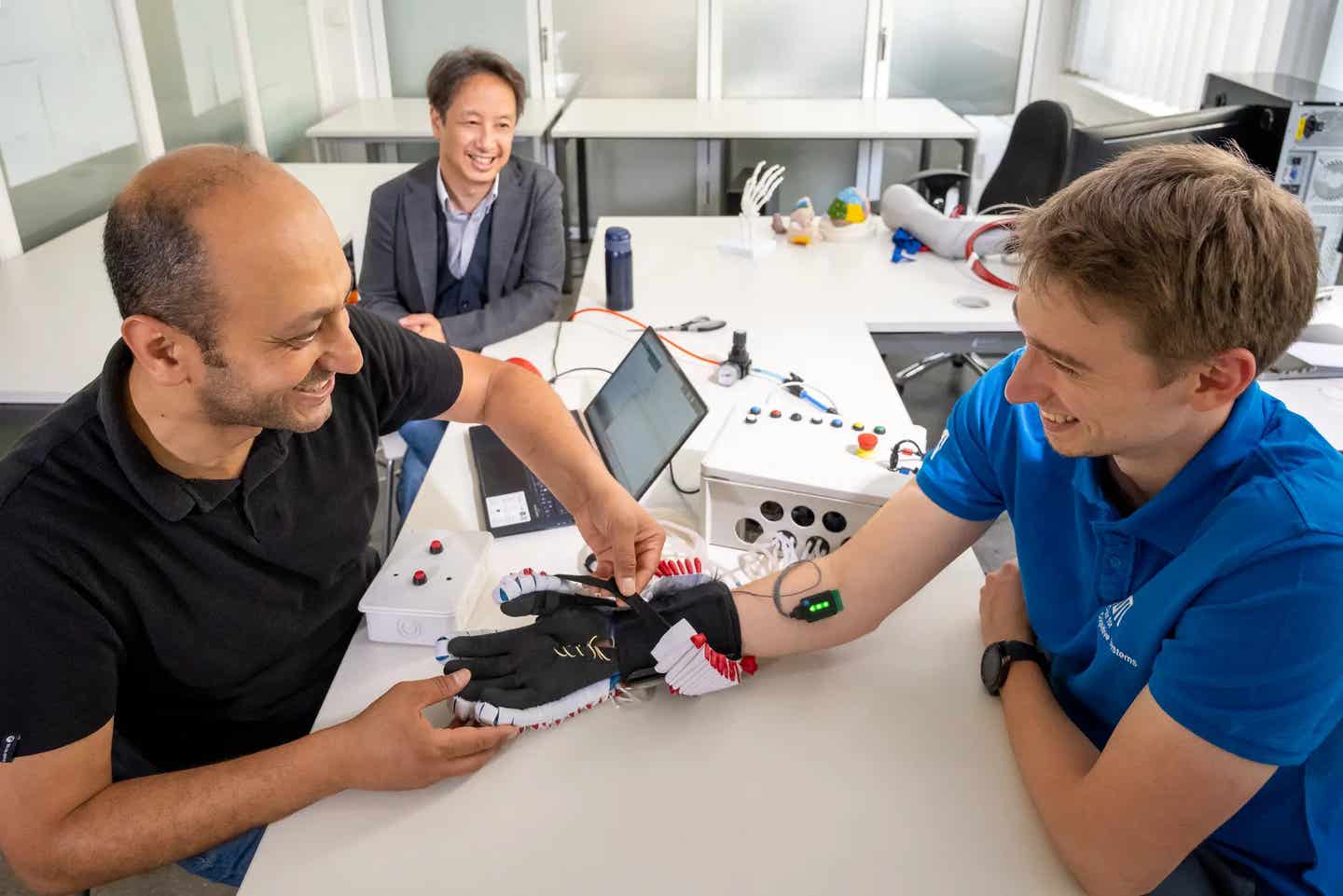 Dr. John Nassour (left) and Nicolas Berberich (right) are testing the newly developed glove. In the background: Prof. Gordon Cheng.