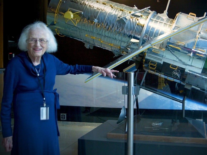 Nancy Grace Roman stands in front of a scale model of the Hubble Space Telescope.