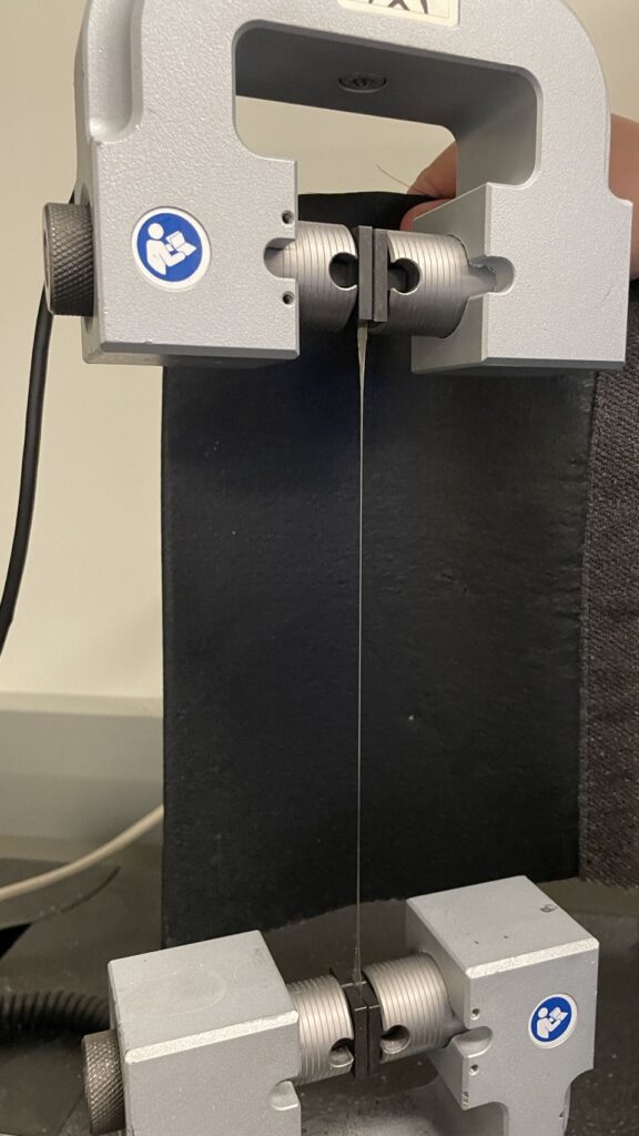 A polymer specimen’s strength and flexibility is tested in the lab.