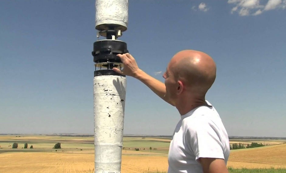 David Yanez stands beside a 6-metre (20-ft.) prototype of a wind turbine without blades