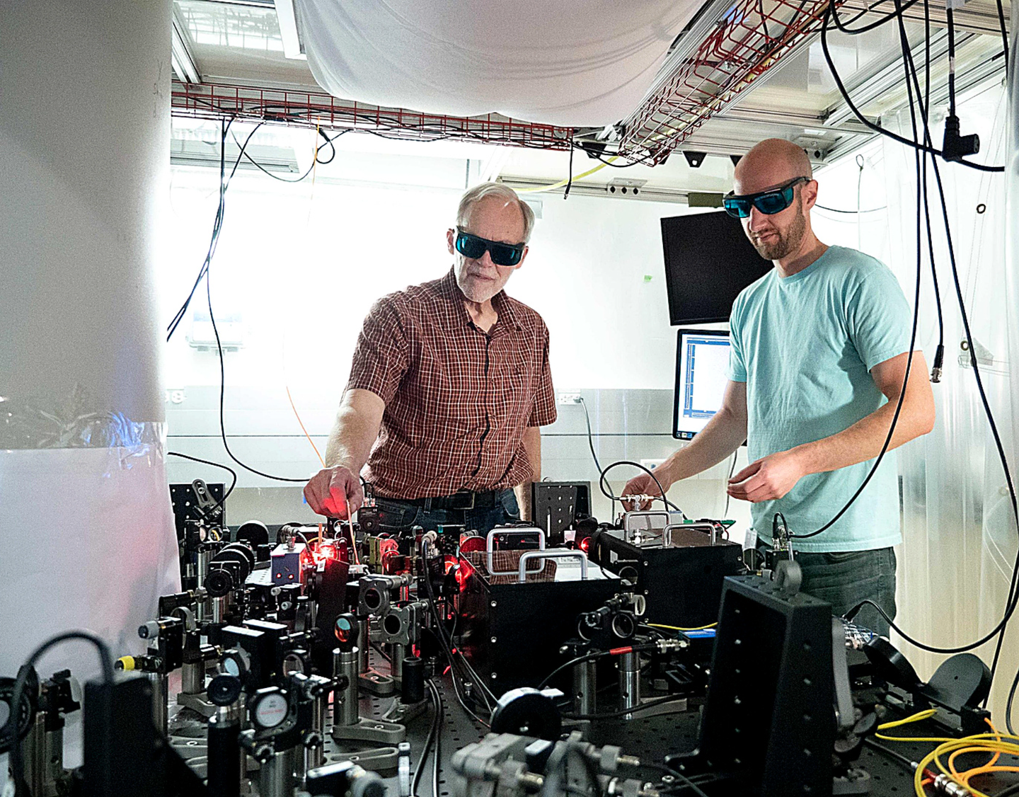 NIST physicists John Bollinger and Matt Affolter adjust a laser system used to trap beryllium ions, creating crystals that could help uncover elusive dark matter.