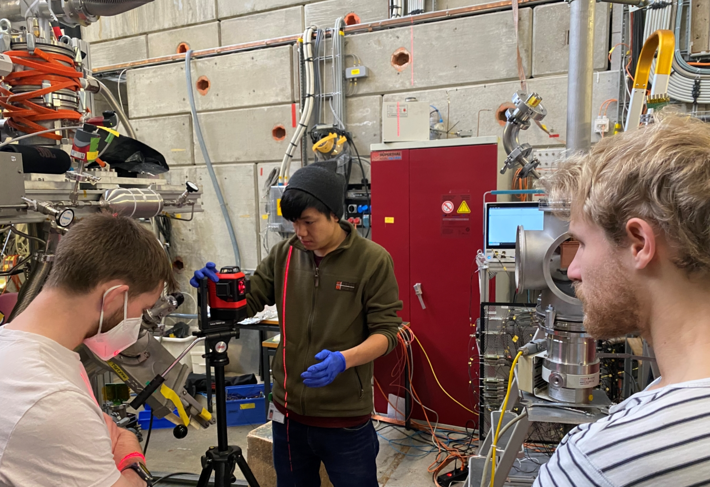 The three doctoral students Robert Waddy, Jesse Zhang and Paul Wegmann (from left to right) are aligning the experiment at PSI, to the beamline.