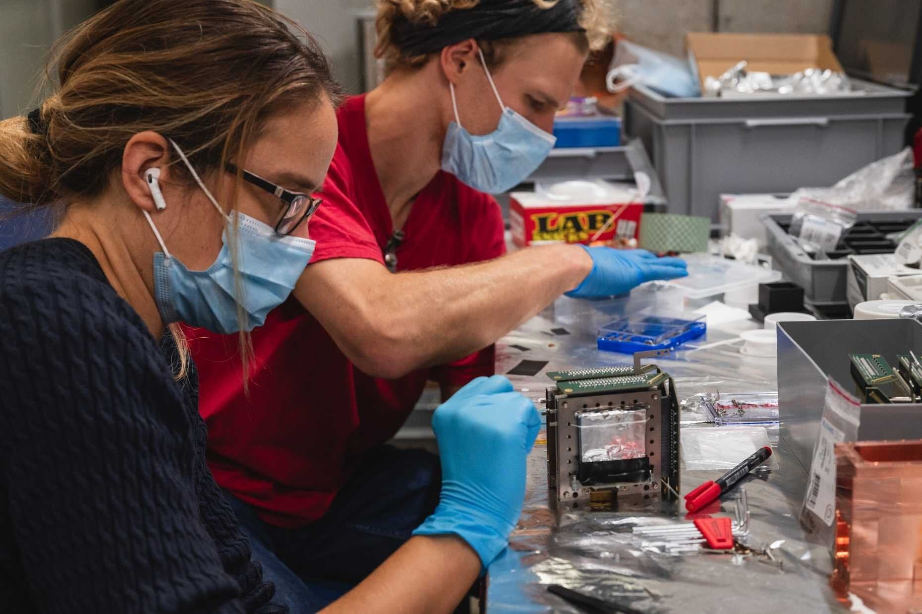 Professor Anna Soter and doctoral student Paul Wegmann are assembling cryogenic silicon detectors for the experiment.
