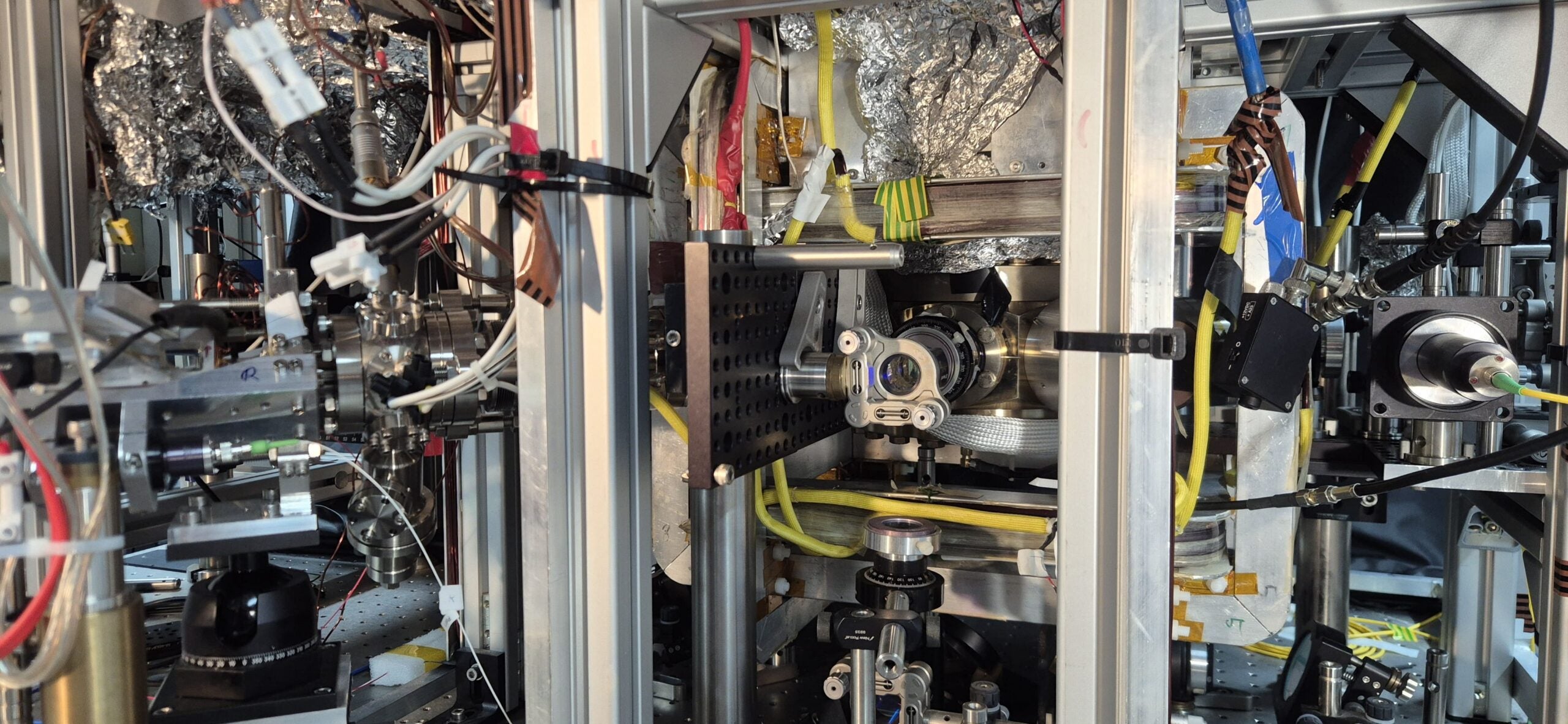 A general picture of the experimental setup. At the heart is a vacuum chamber in which conditions such as those in space mean that atoms can be kept undisturbed. On the left is a 2D MOT, a device that feeds atoms into the science chamber where the atom chip is positioned.