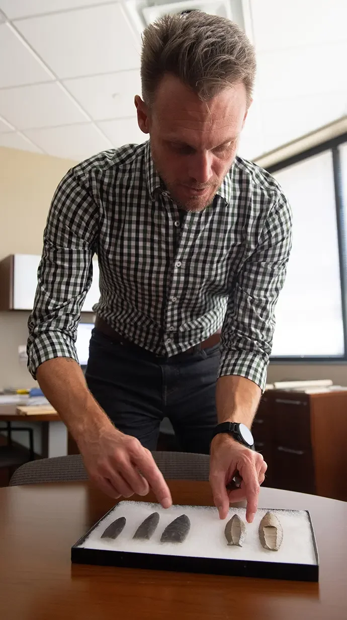 Anthropology professor Jesse Tune explains the differences between Clovis and Cumberland spear points in his office. Tune and University of Alabama anthropologist Shane Miller studied similar projectiles to understand how Ice Age humans learned their landscapes.