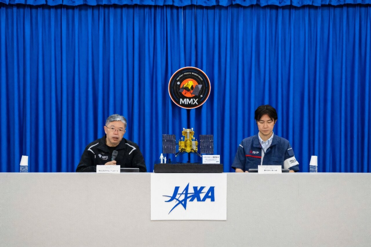 MMX mission manager Yasuhiro Kawakatsu (left) speaks at a press conference at Japan’s Tanegashima Space Center on August 13, 2026.